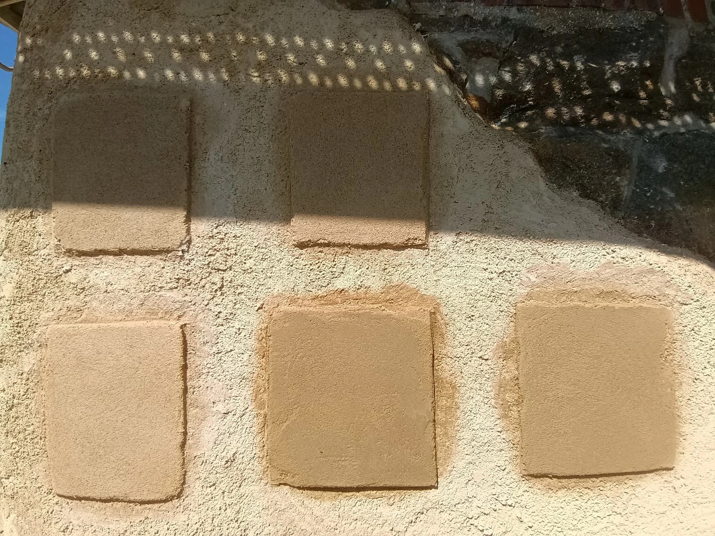 Échantillons d'enduits à la chaux et à la terre sur un mur